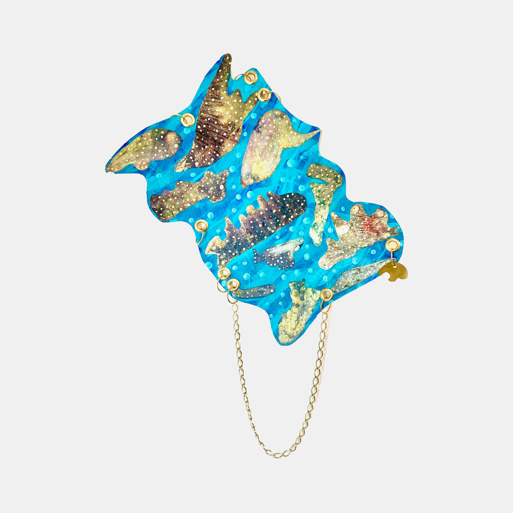 The artwork 'Ocean 1' by Sunny Chapman features abstract swirling patterns in vibrant turquoise blue with metallic gold accents, creating a fluid oceanic movement. The acrylic on paper piece showcases shimmering textures and organic shapes, enhanced by a delicate gold chain detail, measuring 12 by 18 inches.