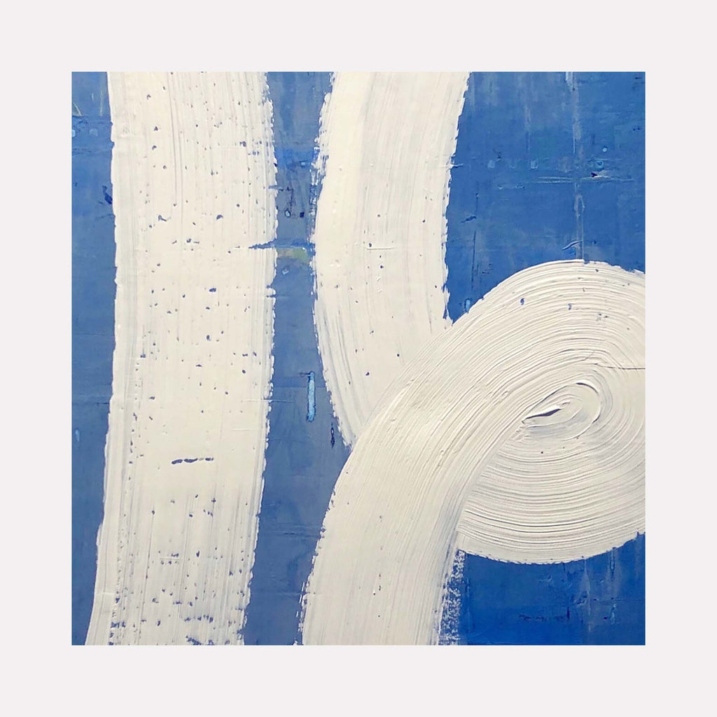 The artwork 'In the Loop' by Shira Toren features bold white curved brushstrokes against a vibrant cobalt blue background, creating a dynamic abstract composition. The textured Venetian plaster application creates a rich, dimensional surface with subtle speckles and variations in the white strokes, showcasing the unique qualities of the medium on canvas.