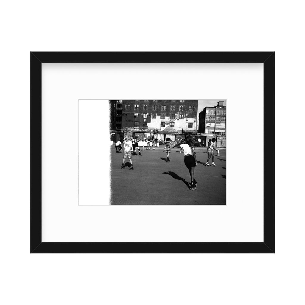 The artwork 'Roller Wave' by Mari Sarai captures a nostalgic black and white urban scene showing people roller skating on a city street. The vintage photograph features dramatic shadows cast by skaters against the pavement, with apartment buildings and storefronts creating a classic cityscape backdrop. The 32x40 inch print artfully preserves a candid moment of urban recreation and community life by Mari Sarai.