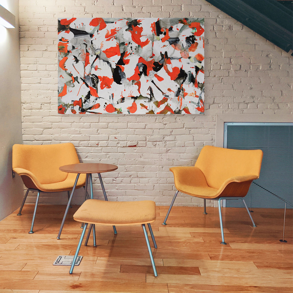 The artwork 'Pantone 021 in the Night' by Linda Lee Nicholas features dynamic abstract expressionist composition with vibrant orange splashes against white and black elements. Bold brushstrokes create angular forms and spontaneous patterns on Dibond surface, measuring 48x73 inches. Displayed above modern orange chairs against white brick wall.