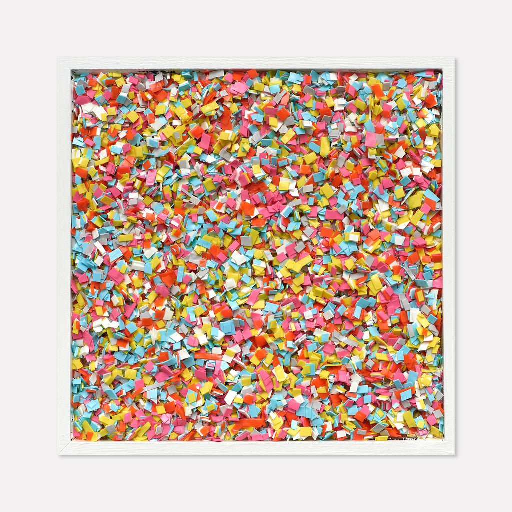 The artwork 'Party Popper' by Lori Kirkbride features a vibrant mosaic of confetti-like pieces in acrylic and resin. Thousands of tiny, colorful fragments in pink, yellow, blue, orange, and red create a dynamic, celebratory pattern across the square panel, capturing the festive energy of scattered confetti.