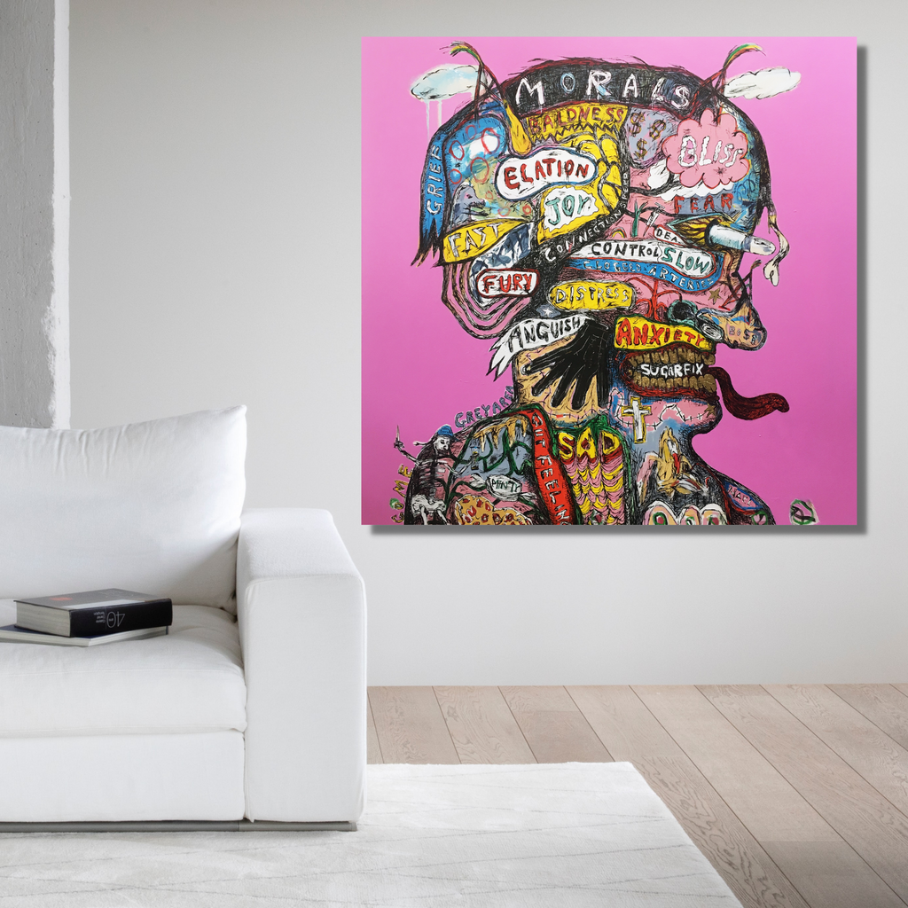 The artwork 'Pink Phrenologist' by Andrew Chan features a vibrant silhouette against a bright pink background. The figure's head is filled with colorful graffiti-style text bubbles and abstract patterns in blue, yellow, and black. The 50x50 inch acrylic canvas combines street art elements with contemporary portraiture, creating a dynamic composition that explores emotional states through typography and color.