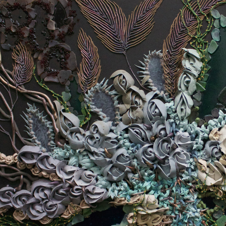 The artwork 'Primordial Arabesque' by Seren Morey features intricate layered patterns resembling underwater coral formations, with delicate feather-like fronds in bronze tones against a dark background. Swirling, textured elements in pale blue-grey and seafoam green create organic shapes, enhanced by glass beads and beach glass that catch light. The mixed media piece combines acrylic and urethane to achieve a dimensional, marine-inspired effect.