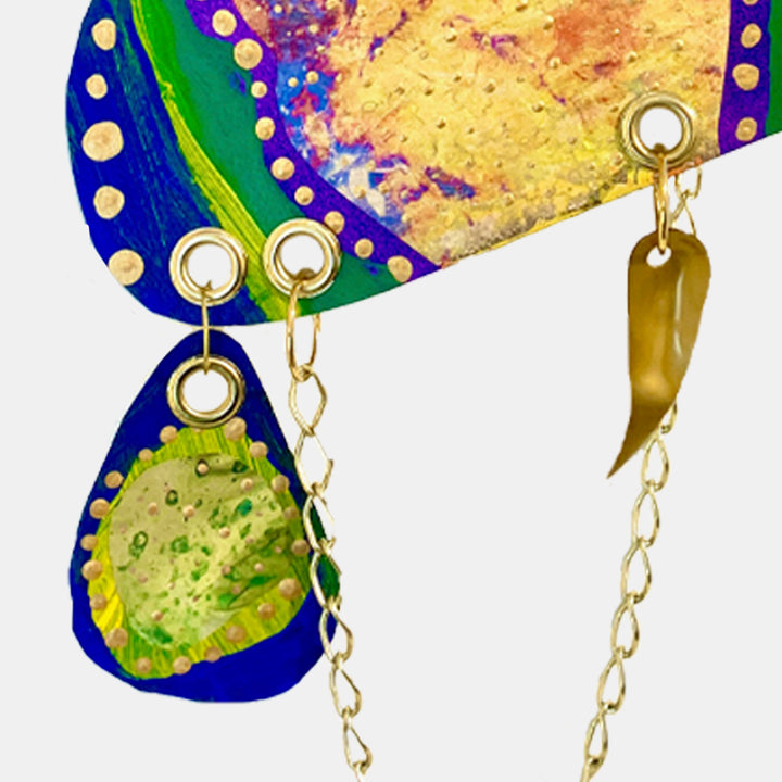The artwork 'Remembrance 1' by Sunny Chapman features vibrant curved shapes with deep cobalt blue borders adorned with cream-colored dots. The composition includes bright green elements and textured golden-yellow areas, connected by delicate gold chain accents. The abstract acrylic painting on paper showcases a dynamic interplay of organic forms and metallic details.
