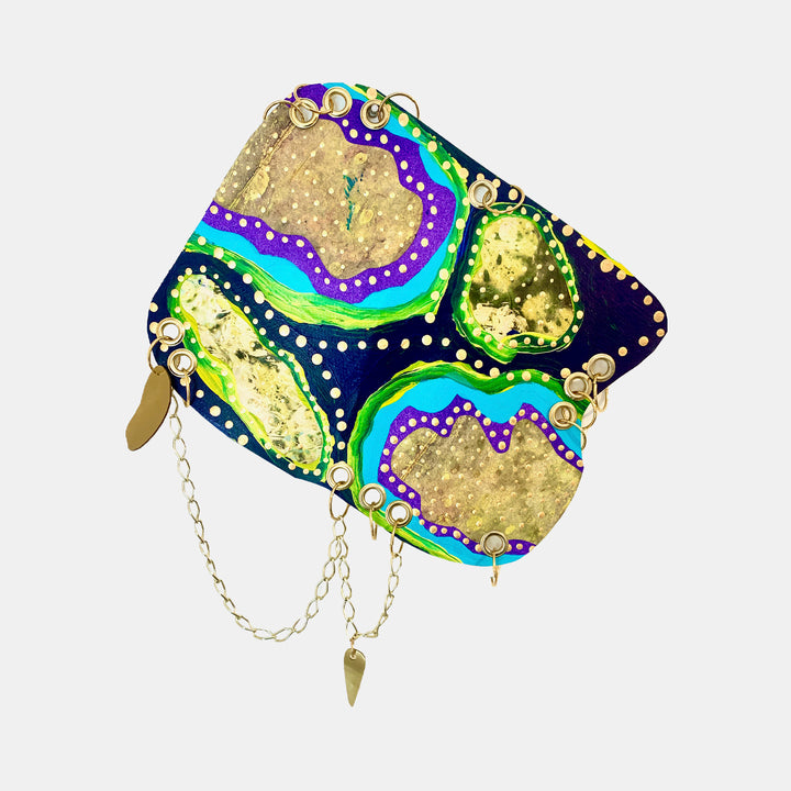The artwork 'Remembrance 4' by Sunny Chapman features abstract flowing patterns in vibrant turquoise, purple, and neon green against a deep navy background. Gold leaf-like textures create organic shapes, accented with delicate white dotted details. The 16x12 inch acrylic painting on paper showcases a psychedelic, fluid style with metallic elements and decorative chain embellishments.