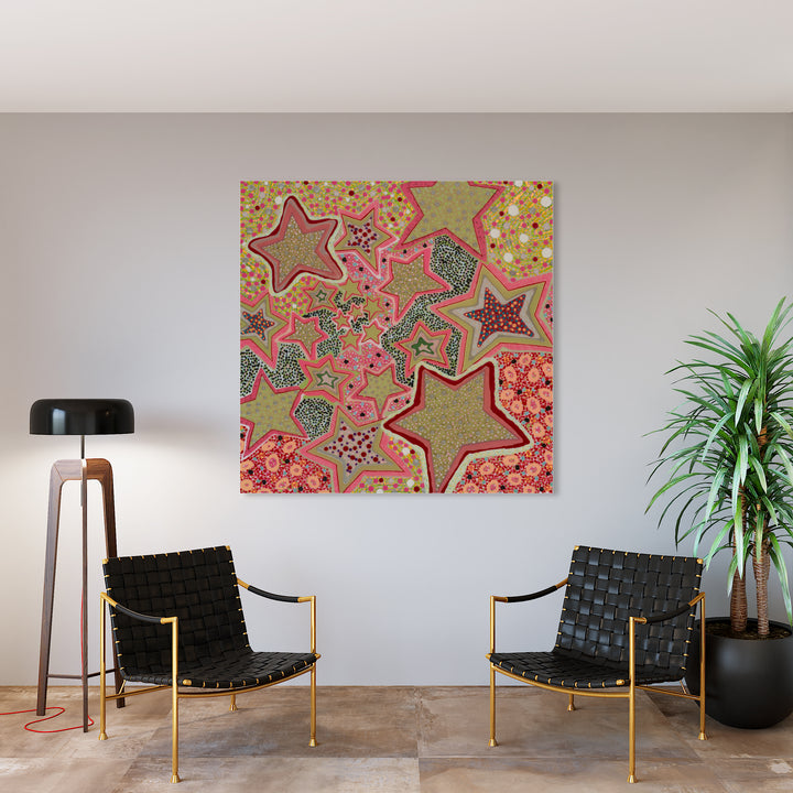 The artwork 'Rockstar' by Lori Kirkbride features a vibrant composition of stylized stars in varying sizes against a coral pink background. Abstract patterns fill each star shape, combining shimmering gold, teal, and pink hues. The mixed media piece showcases intricate textural details created with acrylic polymer and resin on a 60x60 inch panel.