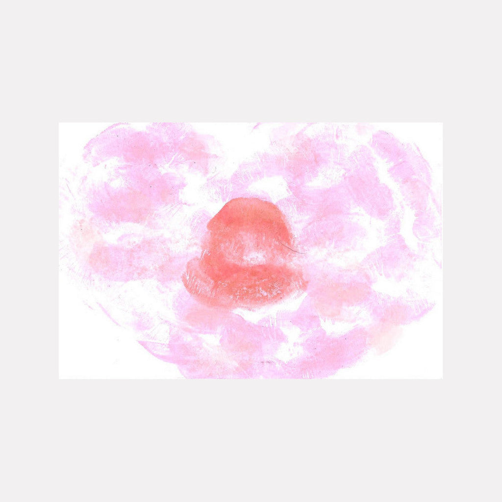 The artwork 'Heart Kiss' by Ronit Levin Delgado features a delicate lipstick impression on white paper, creating a romantic heart shape in coral pink tones. The soft, ethereal composition is surrounded by dreamy, watercolor-like pink wisps that fade into the background, measuring 8.5 x 6.5 inches.