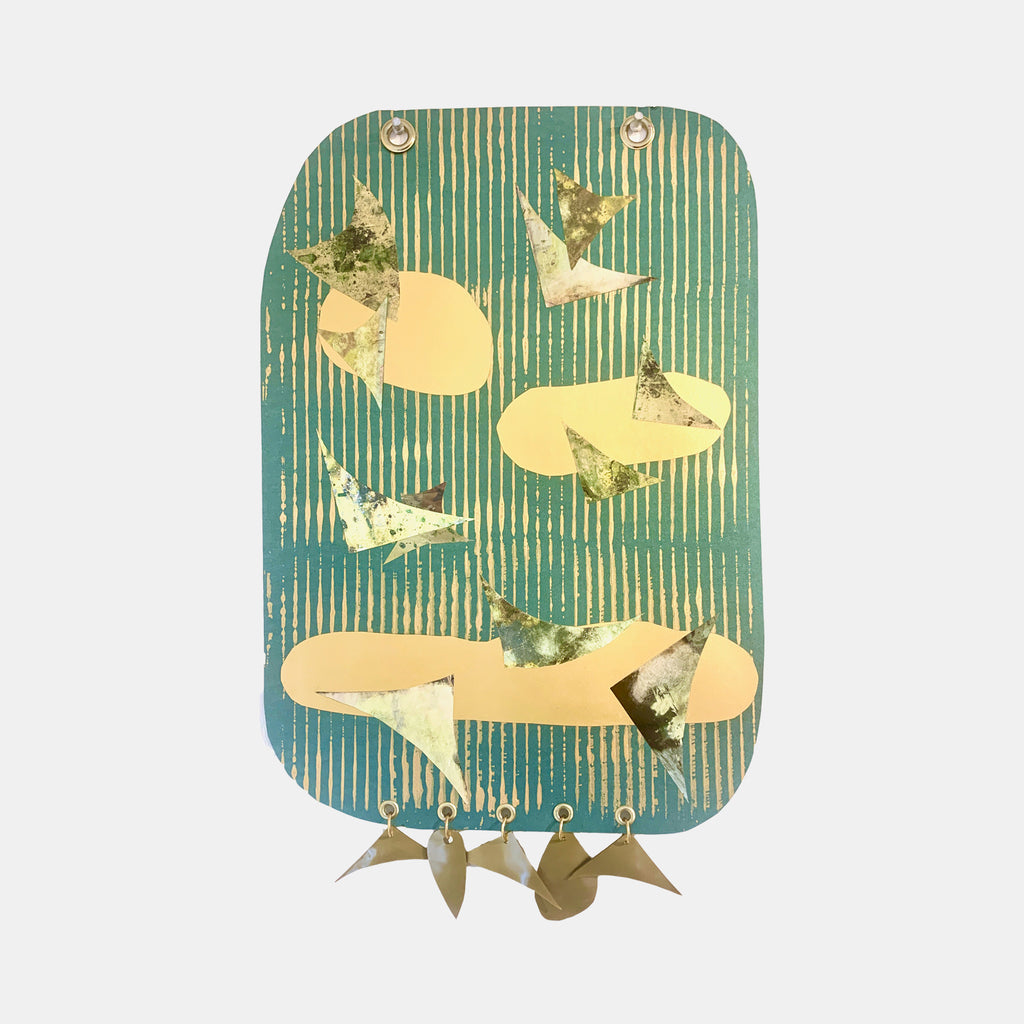 The artwork 'Flight' by Sunny Chapman features metallic butterflies and abstract shapes on a teal-striped background. Created on metallic paper, the collage combines monotype prints with golden accents. Decorative grommets and handmade plastic charms dangle at the bottom, creating a whimsical mixed-media composition.
