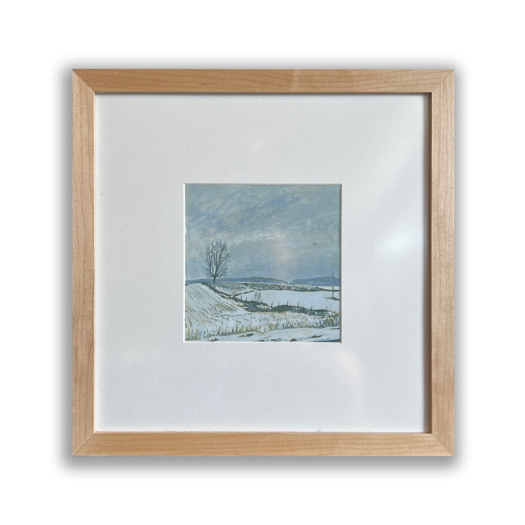 The artwork 'Buckley' by Justin Shull features a serene winter landscape painted in acrylic gouache. A solitary bare tree stands against a misty gray-blue sky, overlooking snow-covered rolling fields. The minimalist composition captures the quiet stillness of a cold winter day, with subtle brushstrokes creating texture in the snowy ground and atmospheric clouds. Professionally framed in natural wood.