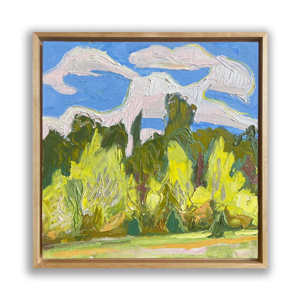 The artwork 'Meadow's Edge I' by Justin Shull features a vibrant impressionist landscape with bold brushstrokes depicting lush green and yellow foliage against a bright blue sky with billowing white clouds. The oil painting showcases rich textural elements through impasto technique, creating a dynamic natural scene framed in wood, measuring 12x12 inches on linen panel.