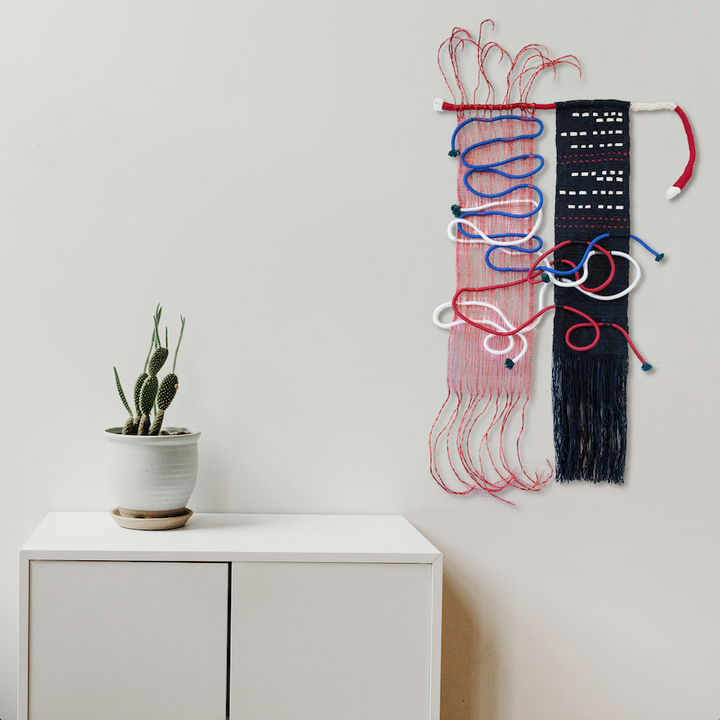 The artwork 'Svo-Bo-Dy! Russian Morse Code' by Kathie Halfin features an abstract wall sculpture combining red and blue copper wire woven intricately with black and white nylon rope. The piece displays a striking contrast of textures, with flowing wire patterns against a structured morse code panel, measuring 46x36 inches in modern contemporary style.