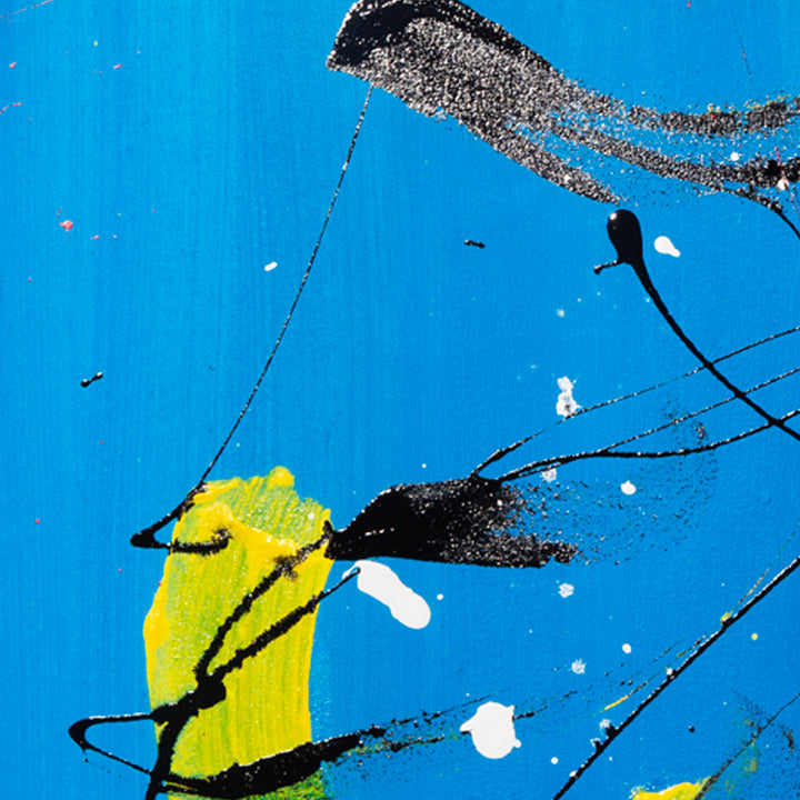 The artwork 'Sinking Below' features bold abstract elements with dynamic black splashes against a vibrant azure blue background. A striking yellow brushstroke emerges centrally, creating dramatic contrast. White speckles dot the composition, suggesting movement and depth. The acrylic and enamel painting demonstrates expressive brushwork and artistic spontaneity on canvas. By Cavier Coleman.