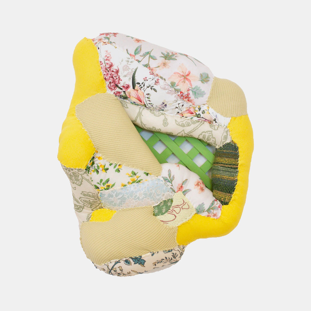The artwork 'Spring Fever' by Hanna Washburn features a textural collage of recycled textiles with vibrant yellow borders and delicate floral patterns. Pale green geometric shapes intersect with vintage-inspired fabric prints, creating a dynamic patchwork composition. The mixed-media piece combines soft pastels and bold accents, showcasing intricate stitching and layered textile elements.