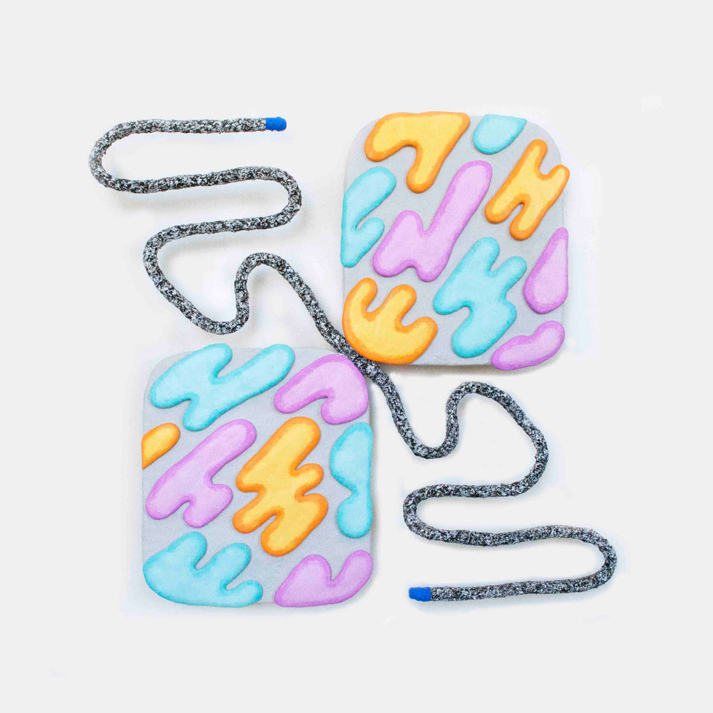 The artwork 'Squeeze' by Ryan Patrick Martin features two abstract panels connected by a sinuous gray textured line. The panels display an interlocking pattern of organic shapes in pastel blue, pink, and yellow tones, painted with acrylic on wood and sculptural materials, creating a playful collision of colors and forms.
