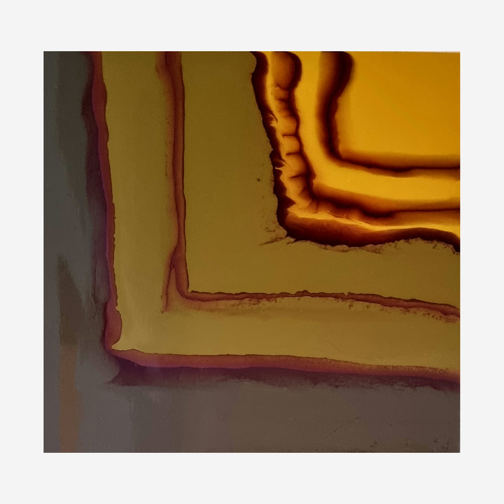 The artwork 'Study 165' by Sabrina Puppin features concentric angular shapes in rich amber and burgundy tones, creating a dramatic layered effect. The synthetic glazes on wood produce flowing, organic edges that contrast with geometric patterns, transitioning from deep mahogany corners to luminous golden center. Abstract contemporary wall art, 12x12 inches.