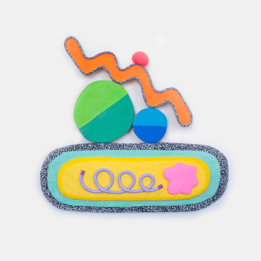 The artwork 'Tasty' by Ryan Patrick Martin features a playful abstract composition with vibrant circles in green, blue, and turquoise, topped by a wavy orange line with a pink dot. The base shows a yellow and mint oval platform with a curling purple line and pink star, all textured with speckled gray borders, created using wood and epoxy clay.