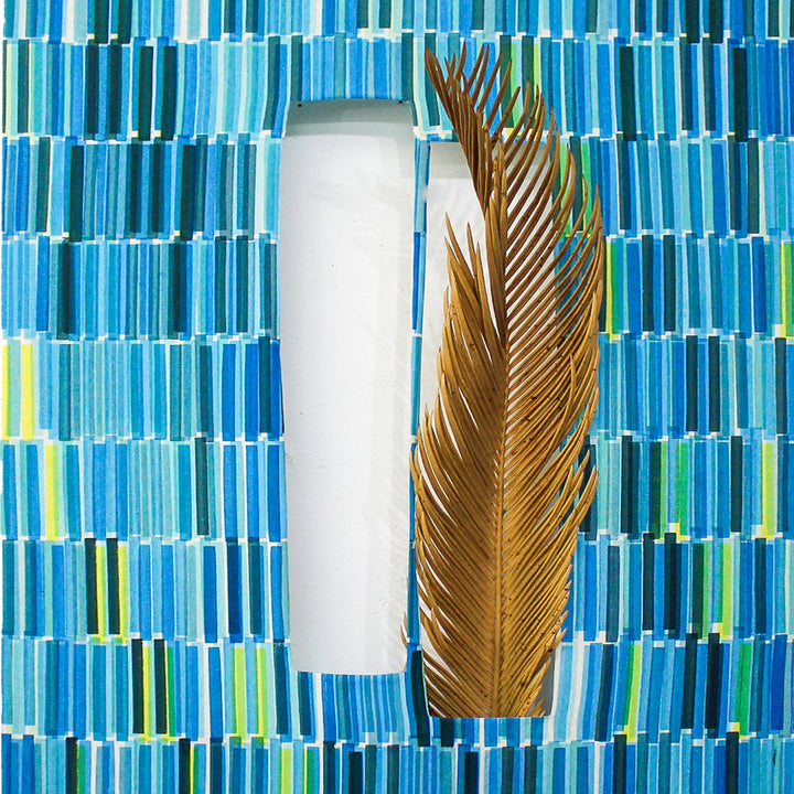 The artwork 'Composite 21' by Molly Koehn features a vertical white cylindrical form alongside a dried brown palm frond, set against a geometric background of mosaic-like blue tiles. The screen-printed pattern on raw silk creates a rhythmic arrangement of turquoise and aqua rectangles with occasional yellow accents. 40x18 inches handcrafted artwork by Molly Koehn.