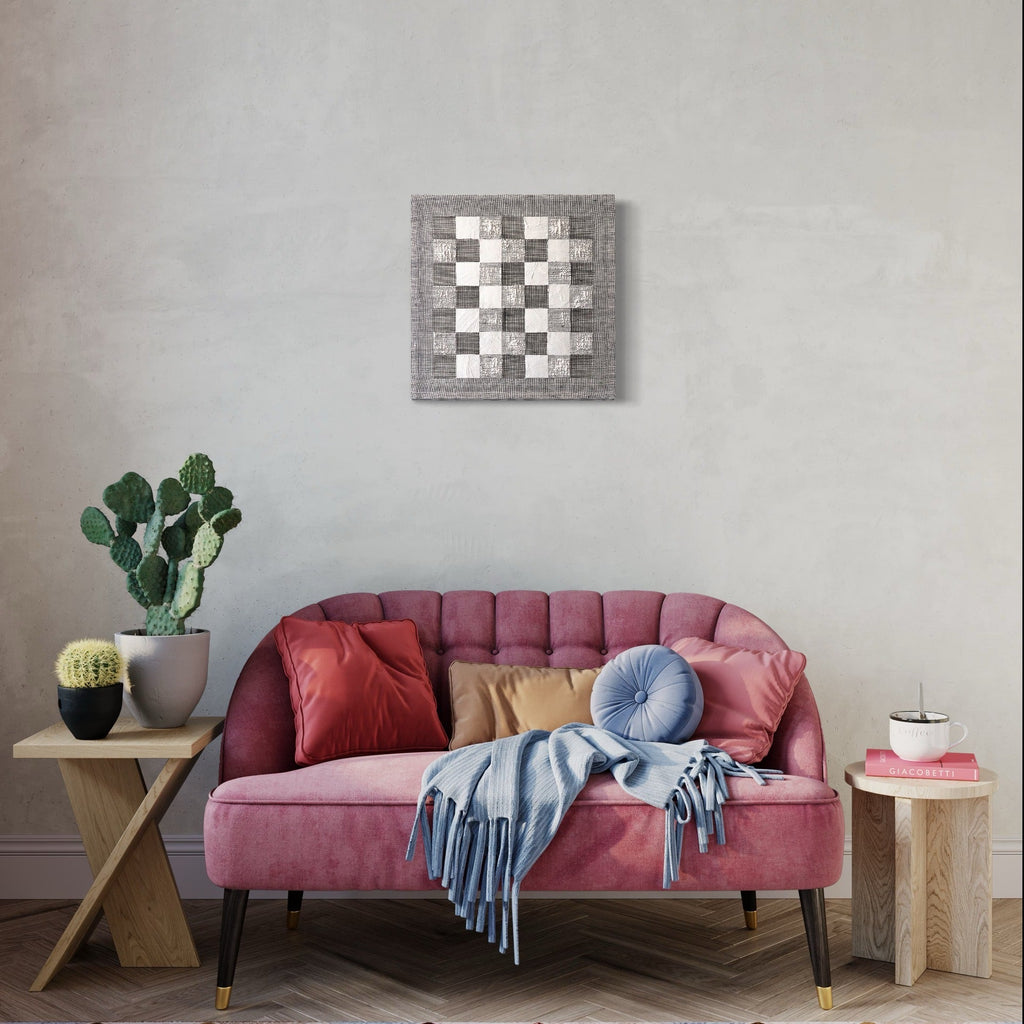 The artwork 'Checkerboard II' by Morgan Hale features a minimalist square composition with alternating white and gray woven pattern, handcrafted in linen and plaster. The textural 18x18 inch piece showcases a classic checkerboard design with a modern, tactile finish, creating a subtle yet striking wall decoration.