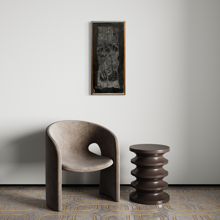 The artwork 'The regional dialect has been crafted over 1000's of years' by Evan Peltzman features an abstract monochromatic composition in ink and plaster on wood panel. The piece displays intricate textural details and geometric forms against a dark background, mounted in a wooden frame. Displayed above modern furniture in a minimalist setting.