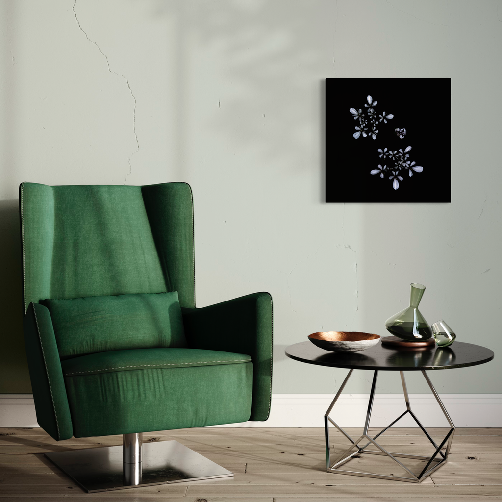 The artwork 'Bur Chervil' by Fabienne Sowa-Dobkowski features delicate white floral patterns against a stark black background, elegantly displayed above an emerald green velvet wingback chair and modern round side table, creating a contemporary minimalist aesthetic. Meta print photography, 22x22 inches.
