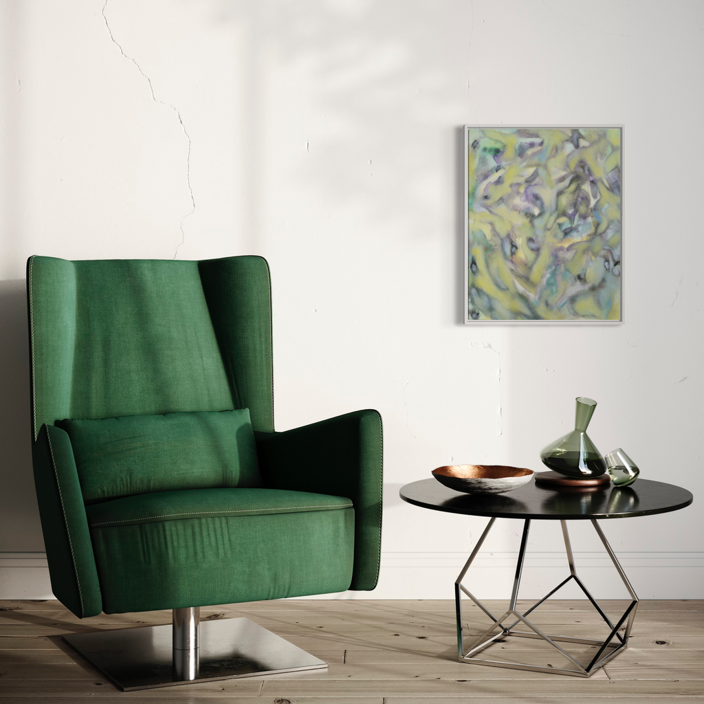 The artwork 'Changing' by Diana Naccarato features abstract fluid brushstrokes in soft yellow and blue hues on canvas, displayed above a modern emerald green velvet armchair and round side table. The 24x20 inch framed acrylic painting creates a harmonious balance with contemporary interior decor.