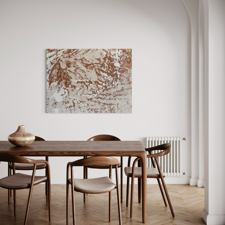 The artwork 'Elemental1' by Cole Douglas features an abstract composition in warm copper and cream tones, creating a marbled, organic pattern reminiscent of natural erosion or flowing water. The acrylic on canvas piece displays textural elements with sweeping brushstrokes and dynamic movement, mounted above a modern dining setting. 48x36 inches acrylic on canvas by Cole Douglas.