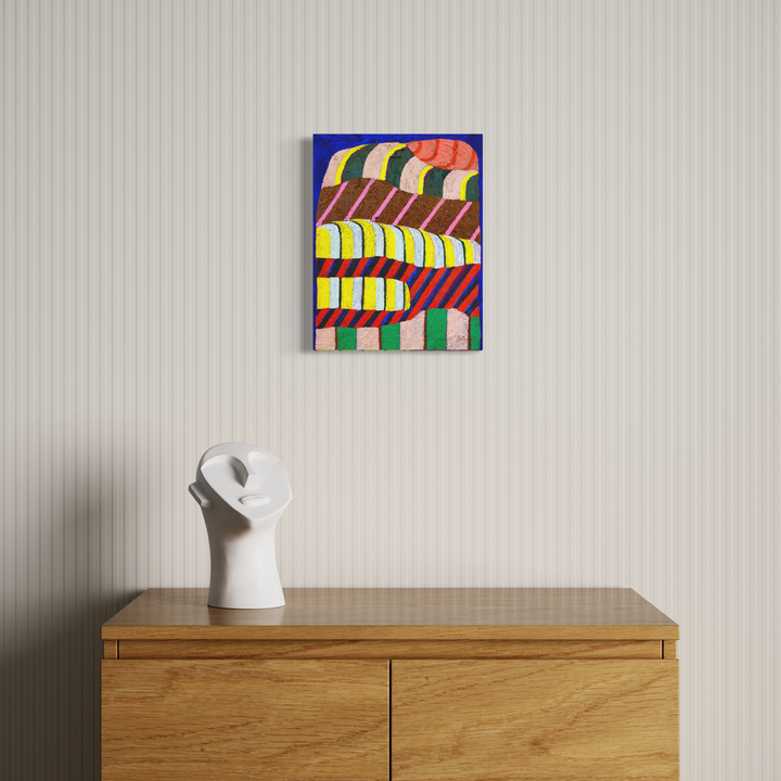 The artwork 'Is It Heavy?' by Natalie Lanese features bold geometric waves in vibrant colors of blue, red, yellow, and brown, creating a dynamic abstract pattern. The textured canvas, created with pumice and flex paste, showcases undulating stripes arranged in a rhythmic, layered composition, mounted on a crisp white wall above wooden furniture. - Natalie Lanese