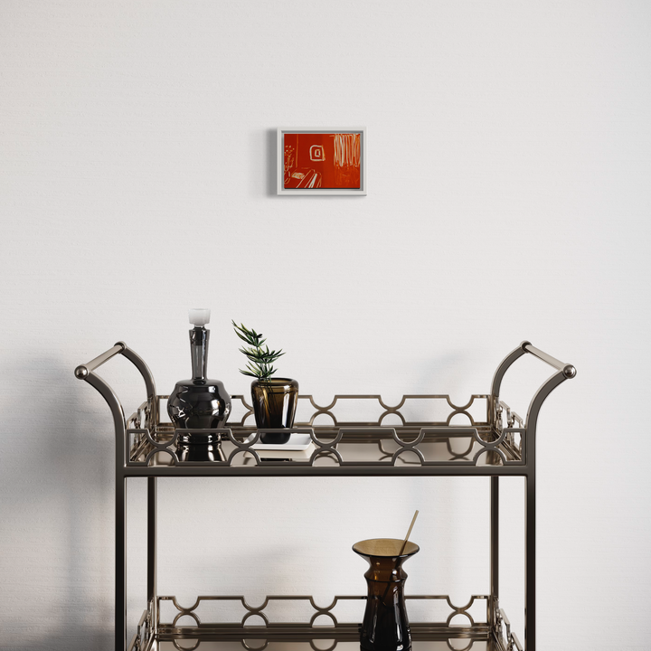 The artwork 'Orange Living Room II' by Chelsie Sunde features a minimalist monotype print in vibrant orange and red tones with abstract geometric patterns, displayed above a vintage-style bar cart with metallic honeycomb details, glass decanters, and a small potted plant, creating an elegant mid-century modern vignette.