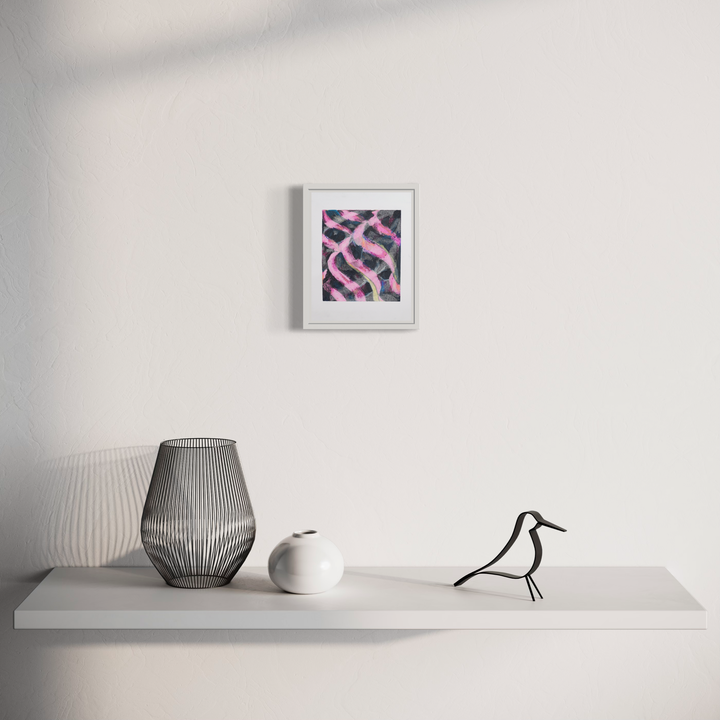 The artwork 'Weaving (1)' by Diana Naccarato features abstract intertwining curves in vibrant pink and black, displayed in a white frame on a minimalist wall above a shelf with decorative vases and a bird figurine. The pencil drawing creates a dynamic pattern that captures movement and flow within its 8x6 inch composition.