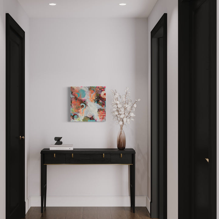 The artwork 'Decision' by Marta Nowicka features abstract swirls of coral pink and turquoise blue, layered with collaged elements on a square canvas. The piece displays dynamic brushstrokes and textural elements, creating a harmonious blend of warm and cool tones. Mounted on a white wall above a sleek black console table, the 20x20 inch artwork showcases contemporary abstract expressionism.