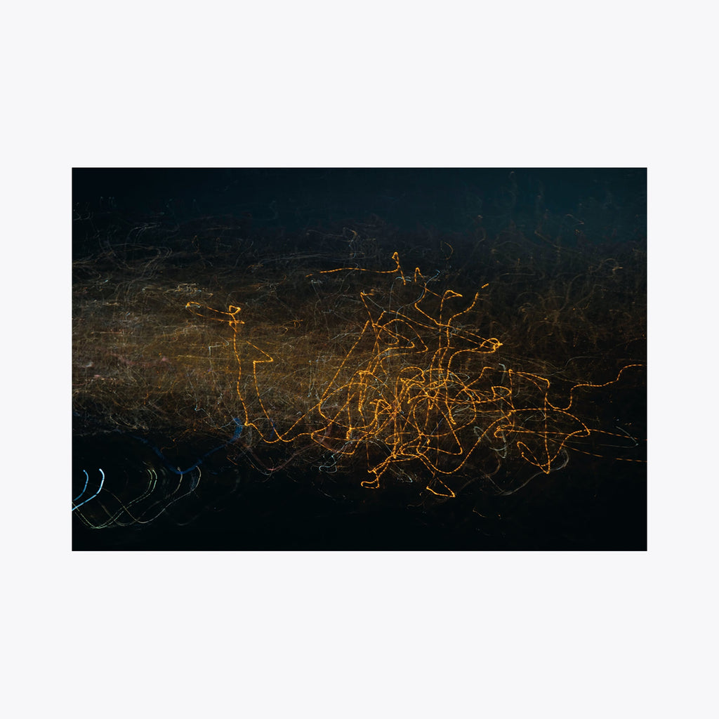 The artwork 'GW Abstraction K' by Chunbum Park features dynamic golden light trails weaving across a dark background, creating an abstract pattern reminiscent of city lights at night. The composition shows illuminated pathways against a deep navy-black canvas, with delicate scratched textures and ethereal movement, presented as a limited edition giclee print by Chunbum Park.