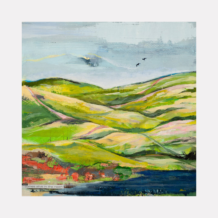 The artwork 'Hills and Valleys #3' by Nicki Adani features a pastoral landscape with rolling verdant hills in vibrant greens and warm yellows, set against a misty blue sky. A deep blue water body rests at the base, with touches of red and coral along the shoreline. The mixed media painting on wood panel captures undulating terrain with a contemporary impressionist style.
