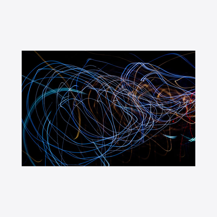 The artwork 'Particle Physics 90' by Chunbum Park features dynamic swirling light trails in electric blue and subtle orange hues against a black background. Abstract luminous lines create flowing patterns reminiscent of subatomic particle movements, capturing kinetic energy through long exposure photography technique. A modern giclee print illustrating the intersection of art and quantum physics.