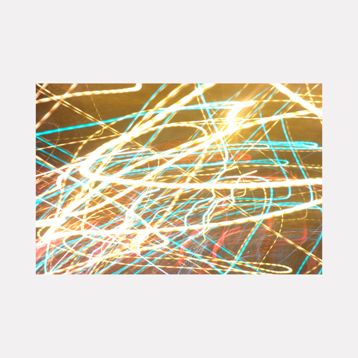 The artwork 'Quantum Physics 007' by Chunbum Park features dynamic light trails in brilliant turquoise and golden yellow, creating an abstract pattern reminiscent of particle movements. The long-exposure digital photograph captures luminous streaks against a dark background, suggesting quantum energy paths and cosmic motion in vibrant intersecting lines.