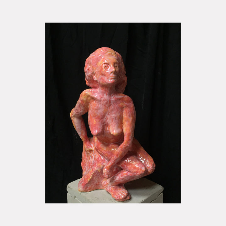 The artwork 'Seated Queen' by Mark LaRiviere features a coral-pink glazed ceramic sculpture depicting a figure in a contemplative pose. The textured surface captures light and shadow, creating a dynamic interplay across the form. The figure is positioned in a relaxed seated posture, measuring 12.5 inches tall. The piece showcases expressive modeling techniques and a vibrant monochromatic glaze treatment.
