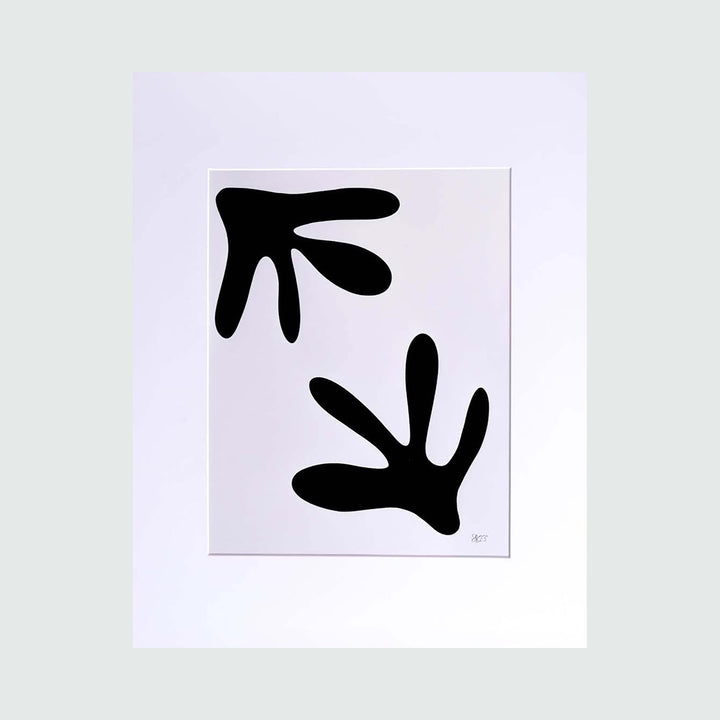 The artwork 'The Morning Meditation Series 6' by Shadia Sabagh features two bold black abstract shapes on white background. The minimalist freehand drawing displays organic, leaf-like forms with curved edges, creating a sense of movement and balance. Limited edition print measuring 20x16 inches.