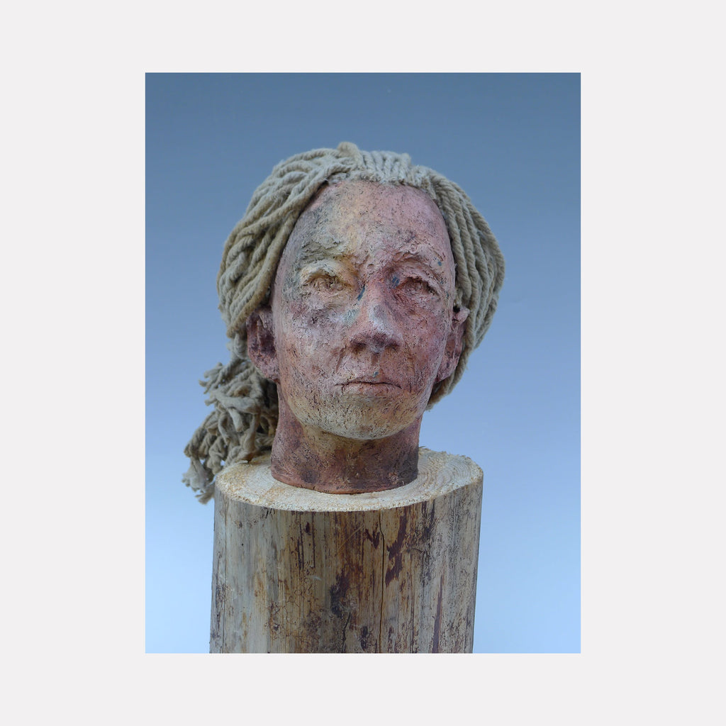The artwork 'Inthetimeofcorona, Head' by Mark LaRiviere features a sculptural ceramic bust mounted on a wooden base. The textured wood-fired surface displays subtle pink and gray tones, with distinctive rope-like textile elements creating a dynamic sculptural form. The piece showcases masterful ceramic craftsmanship combining organic materials and traditional firing techniques.