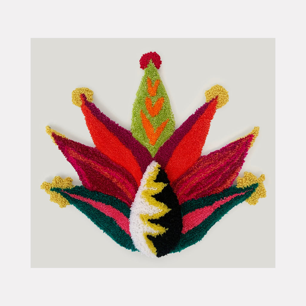 The artwork 'Botanica' by Ana Maria Farina features a vibrant abstract floral design crafted from upcycled fibers on linen. Symmetrical petals in rich burgundy, coral red, and forest green radiate from the center, while decorative spikes in yellow and lime green add dynamic accents. The textural fiber work creates a dimensional, crown-like botanical form measuring 24.5 x 27 inches.