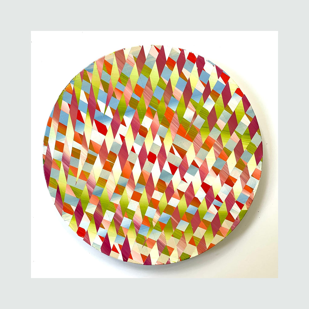 The artwork 'Play' by Elyce Abrams features a vibrant geometric pattern of interwoven diamond shapes on a round wood panel. The dynamic composition showcases a kaleidoscopic array of colors including bright reds, lime greens, soft blues, warm oranges, and pale yellows arranged in a rhythmic diagonal pattern across the 12-inch circular surface, painted in acrylic.
