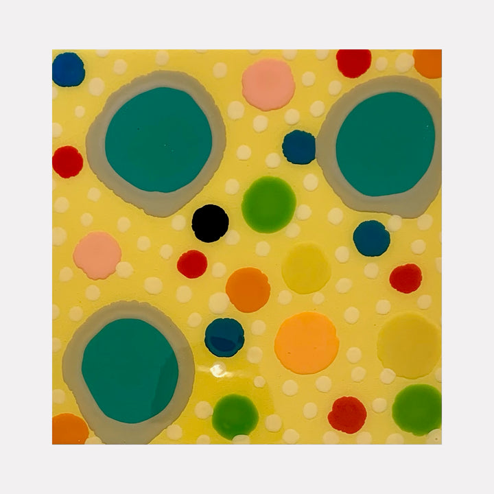 The artwork 'Piece of Cake 886' by Lori Kirkbride features vibrant polka dots on a yellow background. Large teal circles with gray borders are surrounded by smaller dots in red, orange, green, blue, pink, and black. The acrylic and resin artwork creates a playful, modern abstract pattern with a whimsical, retro-inspired design.