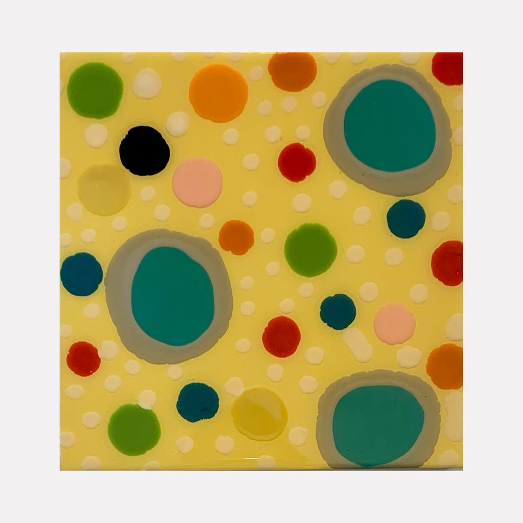 The artwork 'Piece of Cake 887' features playful polka dots in vibrant colors including teal, orange, red, green, and black scattered across a soft yellow background. Three large teal circles with gray borders create focal points, while smaller dots create a dynamic, whimsical pattern in acrylic and resin. By Lori Kirkbride.