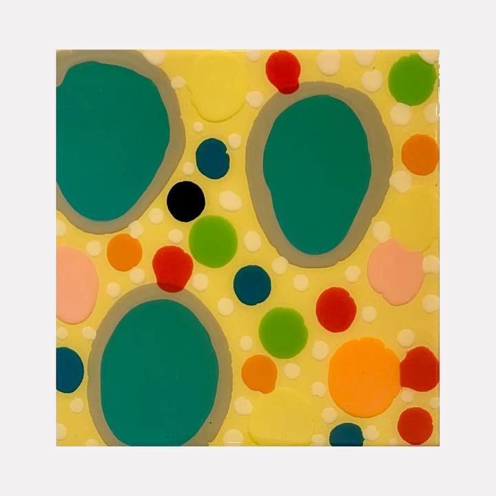 The artwork 'Piece of Cake 946' features vibrant organic shapes on a sunny yellow background. Large teal-green pools dominate the composition, surrounded by playful dots in orange, red, and lime green. The abstract pattern creates a dynamic, bubbly effect using acrylic polymer and resin on panel. By Lori Kirkbride.