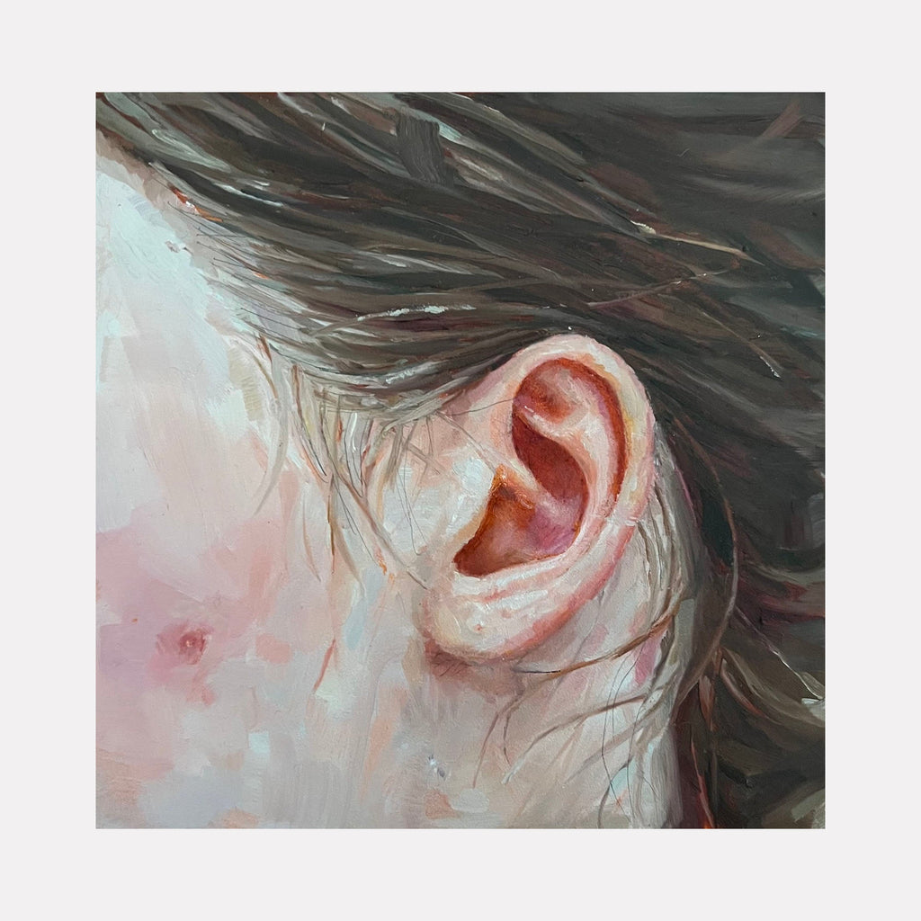 The artwork 'Ear' by Amy Hughes features a close-up oil painting of a human ear against a soft pink and blue background. The painting demonstrates remarkable detail in the curved anatomy of the ear, with delicate brushstrokes creating texture and depth. Rich brown tones of hair frame the composition, creating dynamic movement across the 5x5 inch panel. By Amy Hughes.